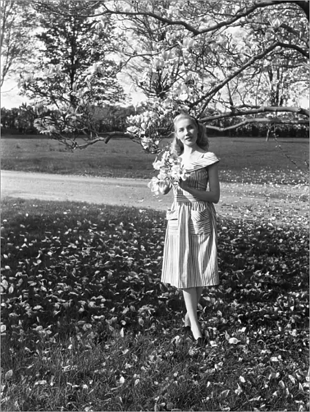 Portrait of young woman standing under magnolia tree in park