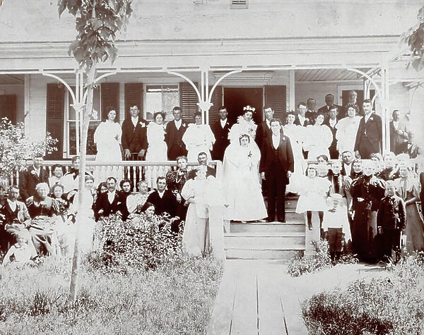 Full-length portrait of a bride and groom with their maids of honor and guests