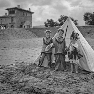 Three children with tent on a beach