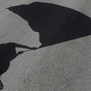 The shadow of a protester holding a flag is seen on the road during a May Day rally