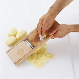Person slicing potatoes using a mandoline