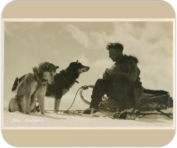 Canadian man sitting on his sled with his two huskies