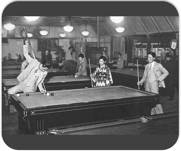 Three young Japanese people play billiards
