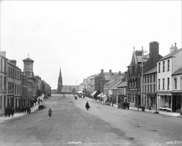 Lurgan - a street scene with motor car and people and shop fronts and church
