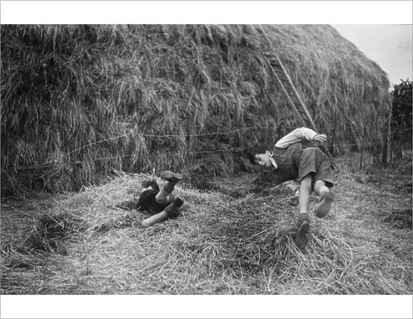 Two boys playing near a haystack