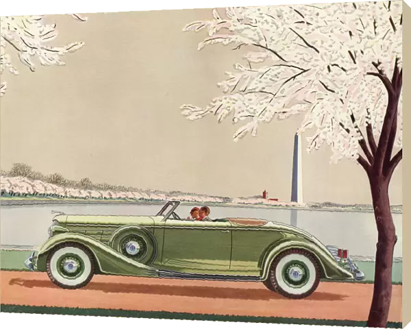 A fine green open-top convertible 1920s sports car passes the Washington Monument
