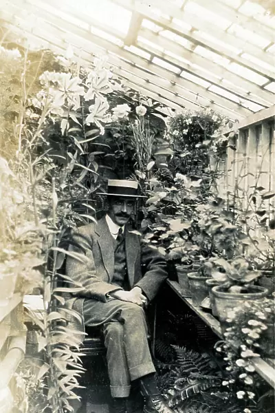 Gentleman Gardener seated proudly in small home greenhouse