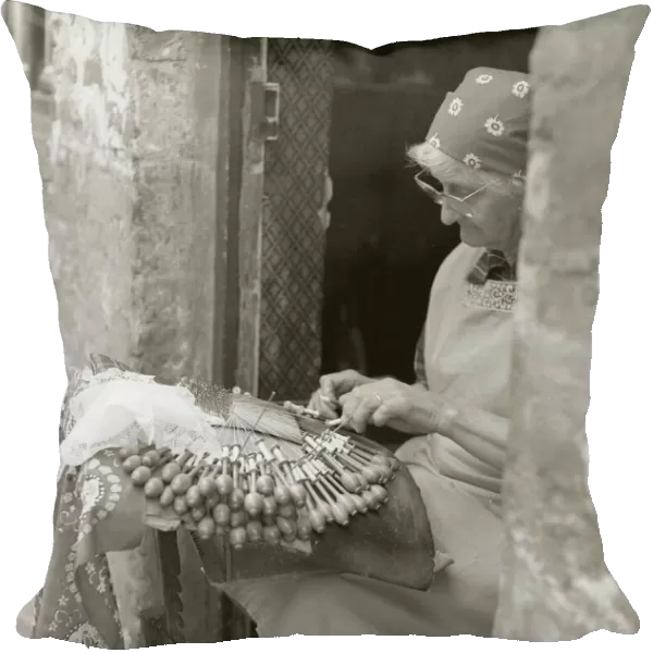 Elderly woman making lace in an open doorway