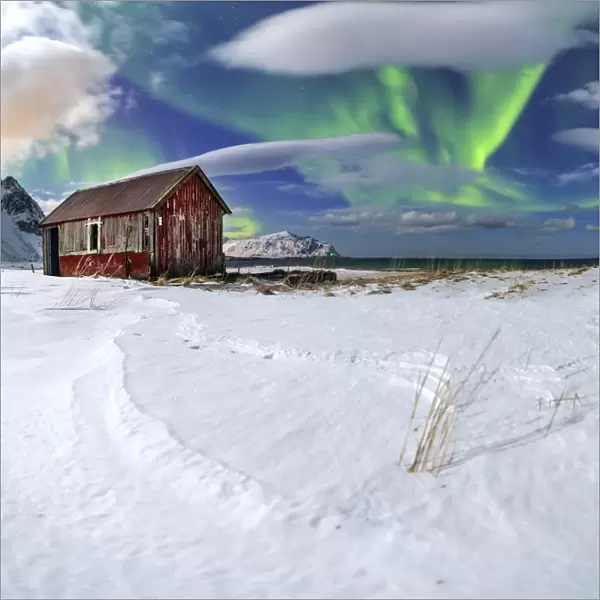 Northern Lights (aurora borealis) over an abandoned log cabin surrounded by snow