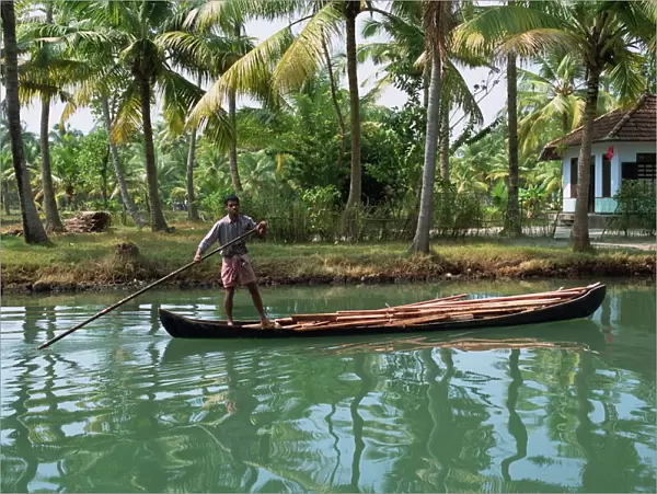 Man with pole pushing boat forwards on a Kerala backwater