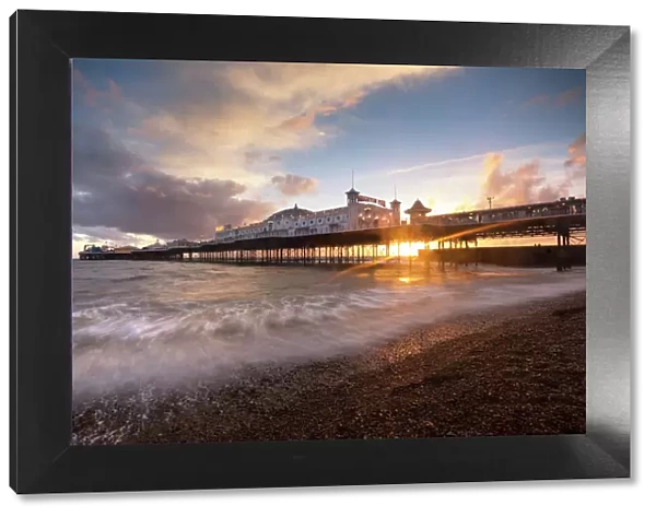 Brighton Pier at sunset with dramatic sky and waves washing up the beach, Brighton