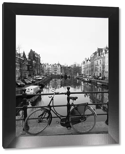 Black and white image of an old bicycle by the Singel canal, Amsterdam
