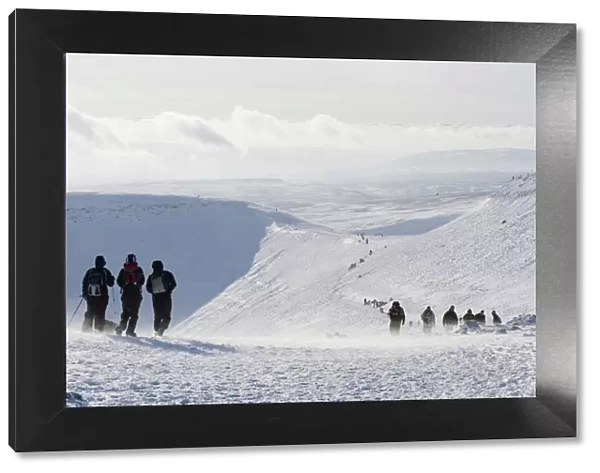 Hikers on snow covered Pen y Fan mountain, Brecon Beacons National Park