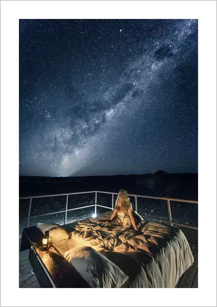 Tourist sitting on a bed outdoor admiring the stars of the Southern Hemisphere, Namibia, Africa