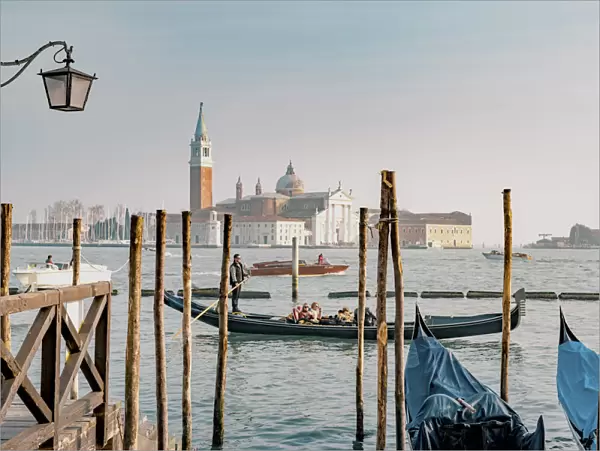 Gondola with tourists at bacino di San Marco with the island of San Giorgio Maggiore