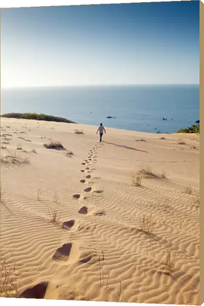 South America, Brazil, Ceara, Morro Branco, a man walks out towards the Atlantic Ocean