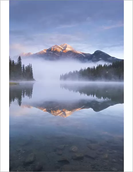 Pyramid Mountain in the Canadian Rockies surrounded by mist and reflected in Pyramid Lake