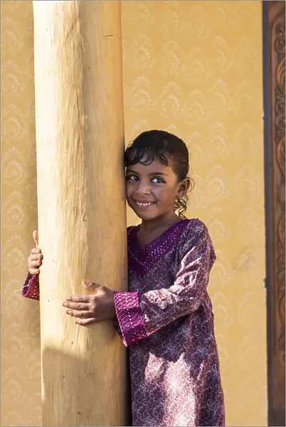 Middle East, Oman, Wahiba sands, a smiley bedouin girl wearing a pretty dress
