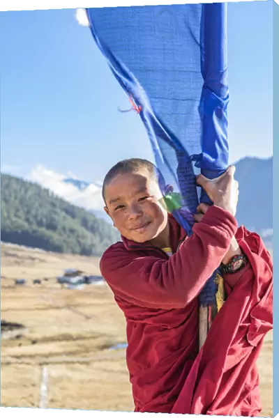 Novice Monks(Child Monk) standing next to a prayer flag in Phobjikha Valley, Bhutan