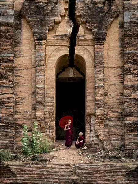 Two novice monks at the entrance to the unfinished Pahtodawgyi pagoda known for a crack