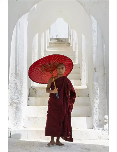 Novice monk with an umbrella standing at staircase hallway at Hsinbyume pagoda, Mingun