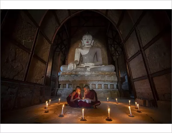 Two novice monks studying inside a temple under big Buddha statue, UNESCO, Bagan