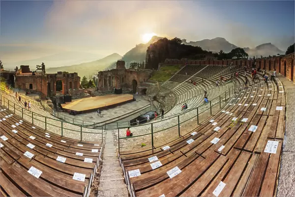 Taormina, Sicily. People sitting in the greek theater with the sun setting