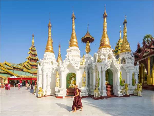 Monk walking by White temple in Shwedagon Pagoda complex, Yangon, Yangon Region, Myanmar