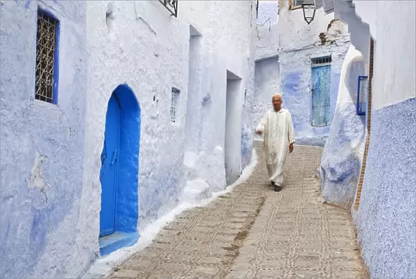 Man in traditional Moroccan clothing walking in the streets of Chefchaouen, Morocco