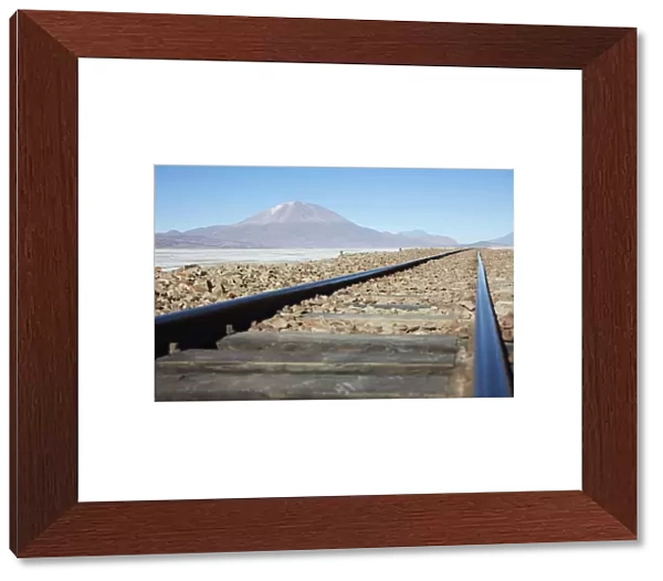 A train track on the Bolivian plateau with the OllagAoe volcano in the background