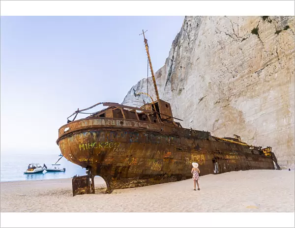 A girl in a hat looking at the shipwreck on Navagio Beach or Shipwreck Beach, Zakynthos, Zante, Ionian Islands, Greece