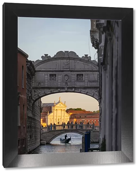Venice, Veneto, Italy. Gondolier under bridge of Sighs and St George church illuminated at sunset