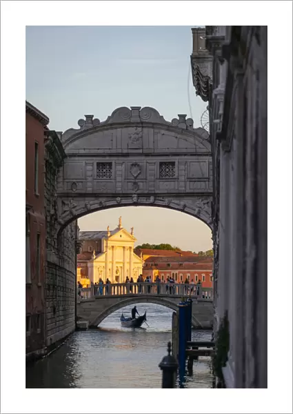 Venice, Veneto, Italy. Gondolier under bridge of Sighs and St George church illuminated at sunset
