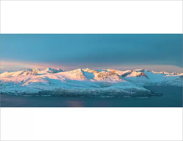 Aerial panoramic view of Senja mountain peaks covered with snow at dawn from Sommaroy, Troms county, Norway
