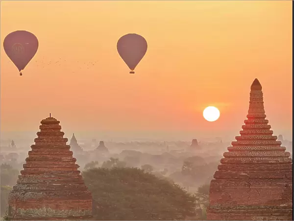 Hot air baloons flying at sunrise over the Bagan Valley archaeological area temples, Old Bagan, Mandalay Region, Myanmar. Bagan was declared a UNESCO World Heritage Site in 2019