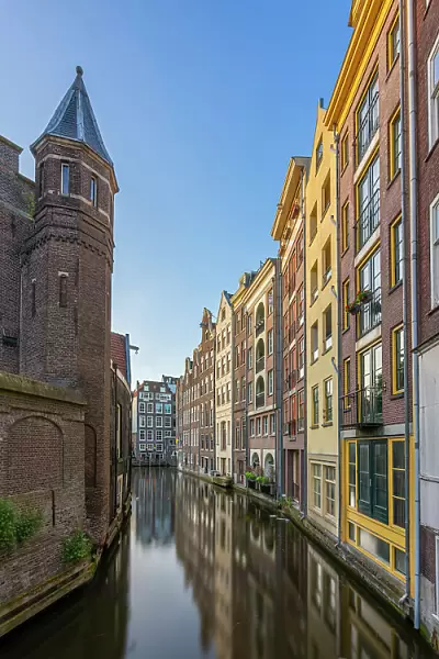 Residential buildings and houses amidst Oudezijds Achterburgwal canal against sky, De Wallen, Amsterdam, Netherlands