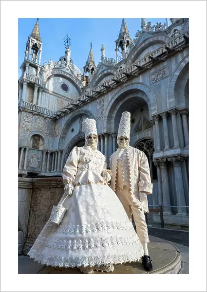 Masked couple posing in front of St Mark's Basilica during the carnival, Venice, Veneto, Italy