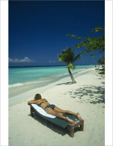 10025750. WEST INDIES Jamaica Negril Woman Sunbathing on lounger on beach near sea