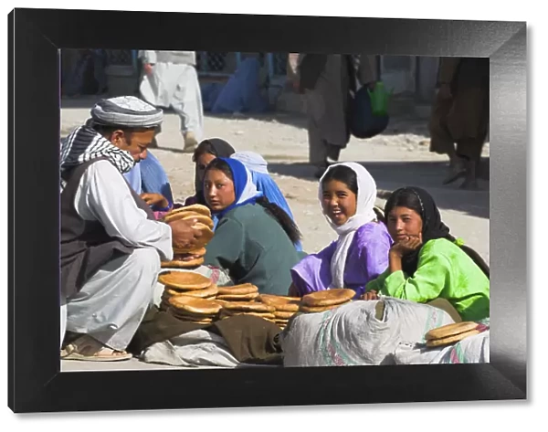 20085103. AFGHANISTAN Mazar-I-Sharif Man buying bread from girls