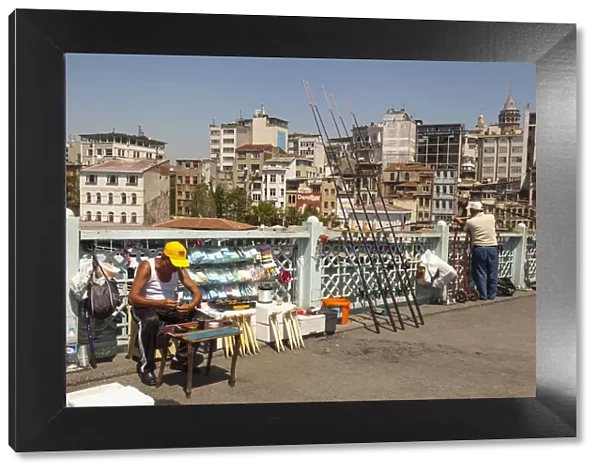 Turkey, Istanbul, Man fishing and man selling fishing tackle on Galata Bridge