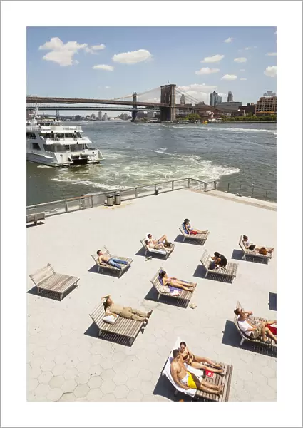People sunbathing beside East River, Brooklyn Bridge and South Street Seaport, Manhattan
