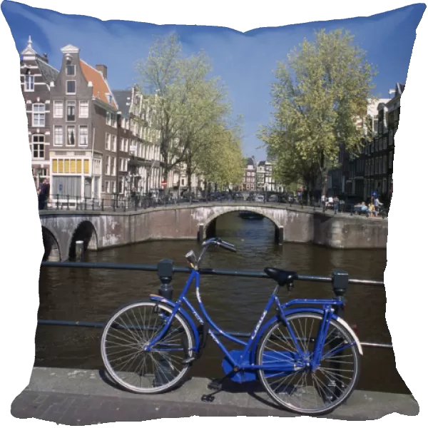 HOLLAND, Noord Holland, Amsterdam Blue bicycle leaning against a railing on bridge
