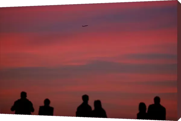 An aircraft flies as people watch sunset in Moscow