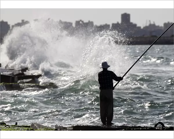 A man fishes along the shoreline in Alexandria