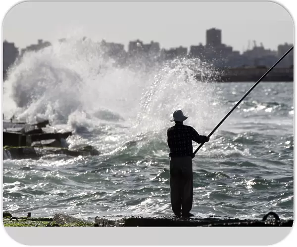 A man fishes along the shoreline in Alexandria