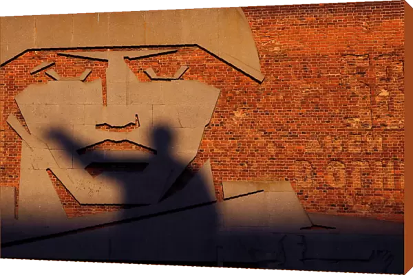 A statue of Soviet state founder Vladimir Lenin casts a shadow on a bas-relief in Volgograd
