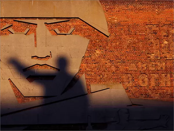 A statue of Soviet state founder Vladimir Lenin casts a shadow on a bas-relief in Volgograd