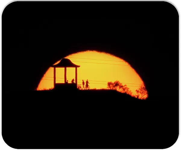 People are silhouetted against the setting sun at El Mirador de la Alemana in Malaga