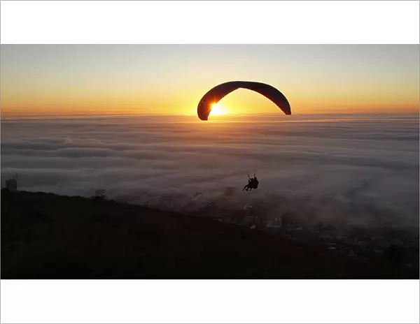 Paragliders take in the last of the days light as a seasonal fog engulfs Cape Town