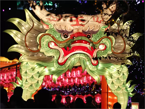 People walk besides a dragon-shaped lantern on display during Lantern Festival celebrations